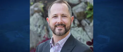 Headshot of Kiernan Gordon against a blue banner