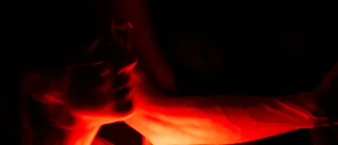 Two dancers stare into a red, glowing orb