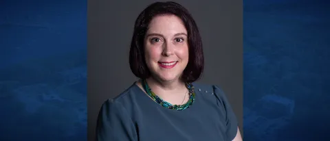Headshot of Dana Villmore against a blue background