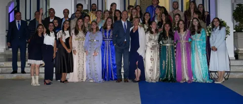 Students, faculty, and administrators pose in front of UNE's Tangier, Morocco, campus building at dusk