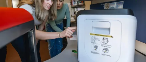 Two students operate a 3D printer