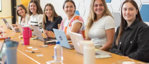 A group of UNE women business students sits around a conference table