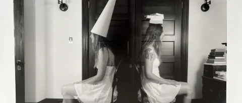 A black and white piece of art depicts one woman in a house sitting in chairs