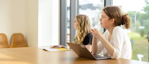 Students listen in a classroom while working on a laptop