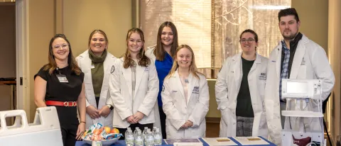 Pharmacy students pose with a UNE alum at a blood pressure clinic