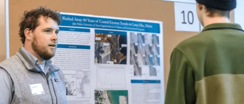 A UNE student presents his climate research to a group of conference attendees