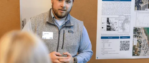 A UNE student presents his climate research to a group of conference attendees
