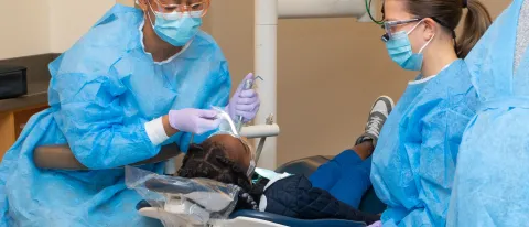 UNE dental students engage with a child patient in the Oral Health Center
