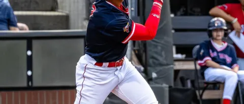 A baseball player follows through with a swing at Hadlock Field in Portland