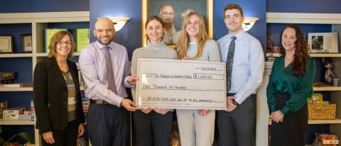 UNE medical students and local health leaders pose holding a large check in the amount of $1,600