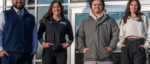 UNE business students pose in front of the Cross Insurance Arena in Portland