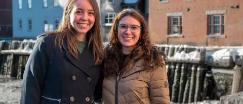 Two women pose in front of the Portland waterfront
