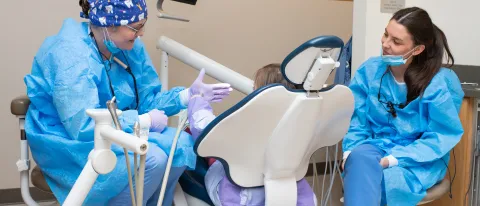 UNE dental students engage with a child patient in the Oral Health Center
