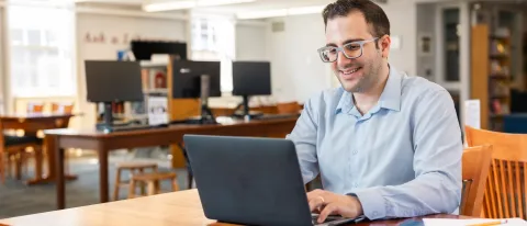 A UNE student works at his laptop in the Portland Campus library