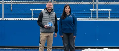 UNE student Ty LeBlond poses with professor Aimee Vlachos at UNE's football stadium