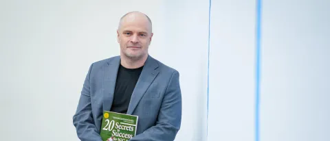Photo of Norm O'Reilly against white background holding a book he has authored