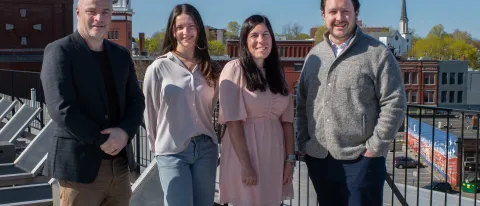 UNE business and Atlantic Hospitality leaders pose in front of the Biddeford skyline