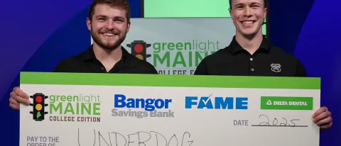 Joey Stanizzi and Dylan Schuett ’25 hold a large check for their Greenlight Maine win