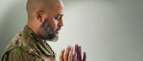 A man prays while wearing a U.S. military uniform