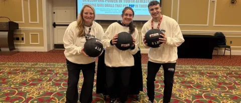UNE student Aidan Curran poses with his research collaborators, all three are holding medicine balls