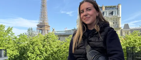 UNE student Cally Gudroe poses in Paris with the Eiffel Tower in the background