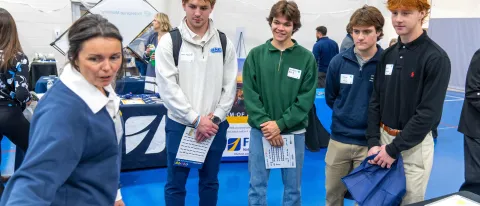 A group of male students speaks with a job recruiter