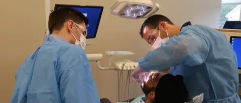 COM student Govind Kamboj plays a patient while CDM student Greg Stein explains a procedure to COM student Ryan Healy