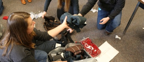 Medical students Allison Hockman and Tess Strand pack baby carriers with freshman Marissa Laramie 