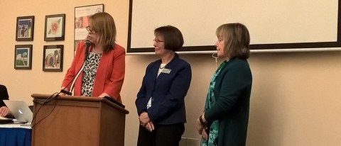 RSU 21 Superintendent Katie Hawes speaks at the podium while Susan Gray, UNE's associate dean of the College of Arts and Science
