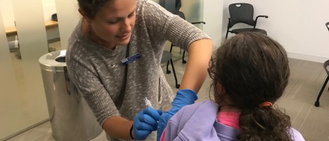 Nursing student Elizabeth Alvin administers a flu shot to a health fair visitor