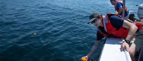 Andy Robinson (M.S. Marine Sciences, ’21) places oranges in the water in Biddeford Pool to track surface current movements.