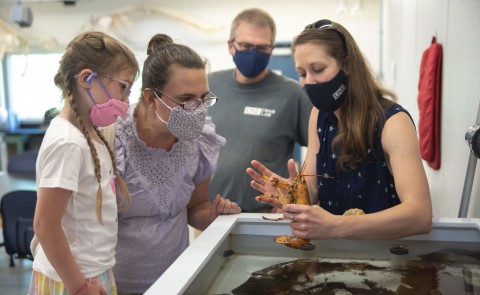 Girl and family meet yellow lobster in Marine Science Center