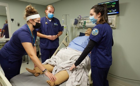 Nursing students stand around a patient simulator in UNE's Interprofessional Simulation and Innovation Center