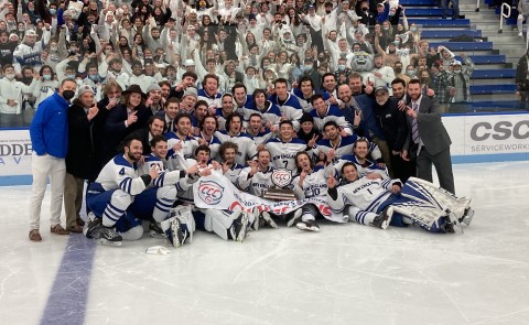A large crowd of students and ice hockey players pose on the ice after the Nor'easters men's ice hockey team won the CCC championship