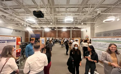 Physical therapy students present at their annual research symposium. Crowds gather to watch presentations
