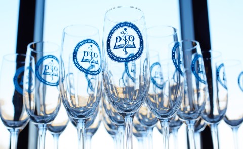 Champagne flutes branded with the UNE COM logo are arranged on a table