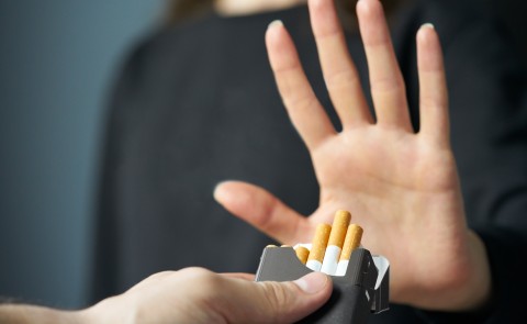Stock image of a person raising their hand "no" to an offer for a cigarette