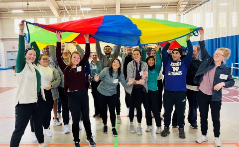 students holding up colorful parachute
