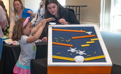 A child plays with an adaptive toy at a display table