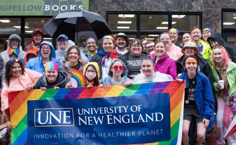 UNE community members gather with a UNE Pride banner in Monument Square in Portland