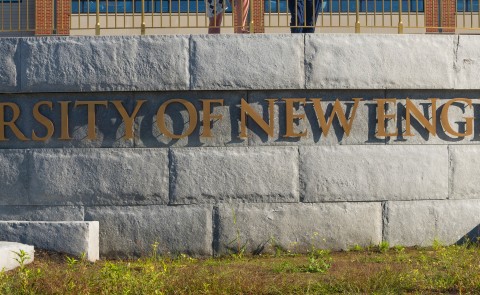 A metal sign against a brick wall reads "University of New England" 