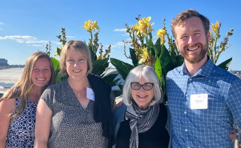 Four researchers pose in front of a flowers outside
