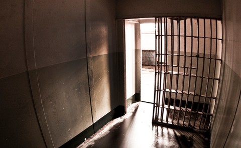 A dark photo shows the silhouette of a jail cell