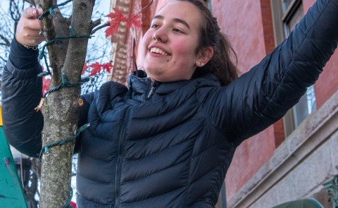 A student smiles as she hangs lights in front of Biddeford's City Theater