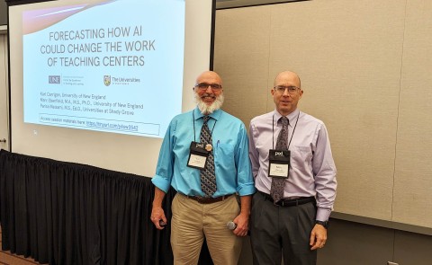CETL's Karl Carrigan and Marc Ebenfield pose in front of a slideshow presentation at a conference