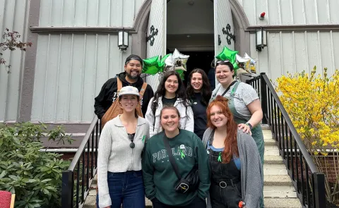 A group of UNE students poses in front of UNE's Ludcke Auditorium 