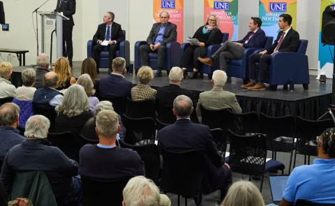 UNE President James Herbert introduces four panelists and a moderator onstage