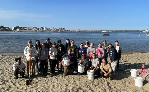 A group of students pose with buckets on Freddy Beach after cleaning up the sands