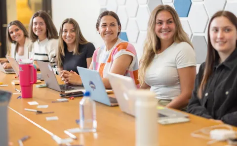 A group of UNE women business students sits around a conference table