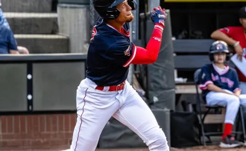 A baseball player follows through with a swing at Hadlock Field in Portland